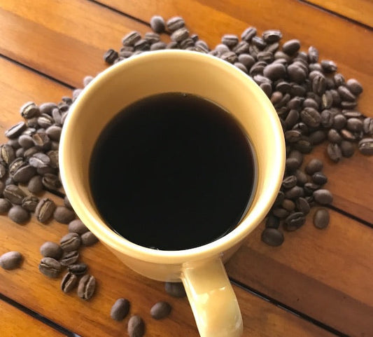 pic of coffee in mug surrounded by roasted coffee beans