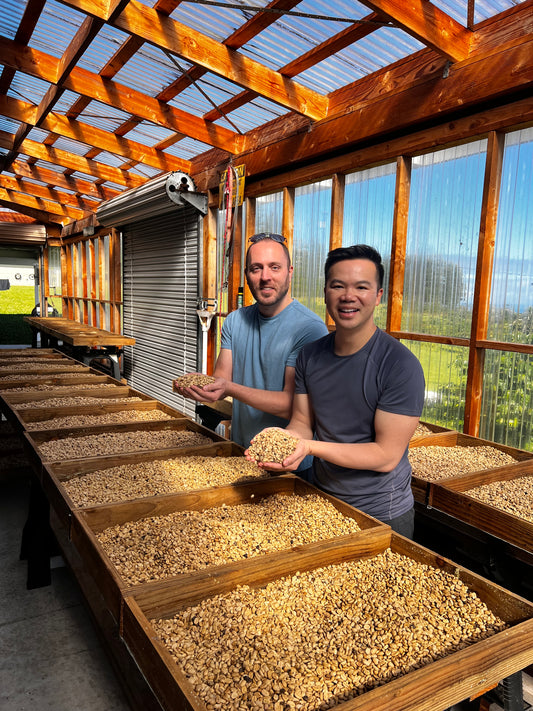 image of two farm tourist posing with handful of coffee parchment at Hog Heaven Coffee farm tour