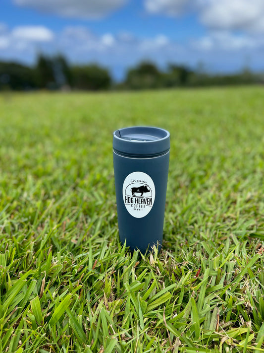 Coffee mug with Hog Heaven Coffee sticker against nature background